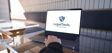 Laptop z logo LegalTech na biurku.